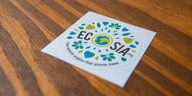 Ein Sticker von Ecosia liegt auf einem Holztisch