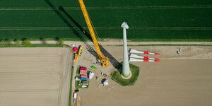 Ein neues Windrad wird mit Hilfe eines großen Krans montiert (Luftaufnahme)