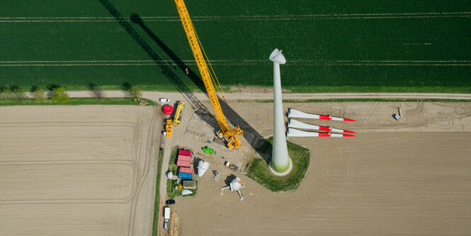 Ein neues Windrad wird mit Hilfe eines großen Krans montiert (Luftaufnahme)