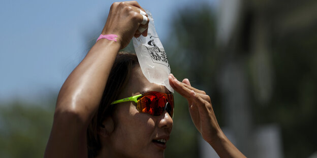 Eine japanische Beach-Volleyballerin drückt sich ein Eispaket an die Stirn