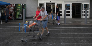 Menschen laufen mit einem EInkaufswagen aus einem US-Supermarkt hinaus