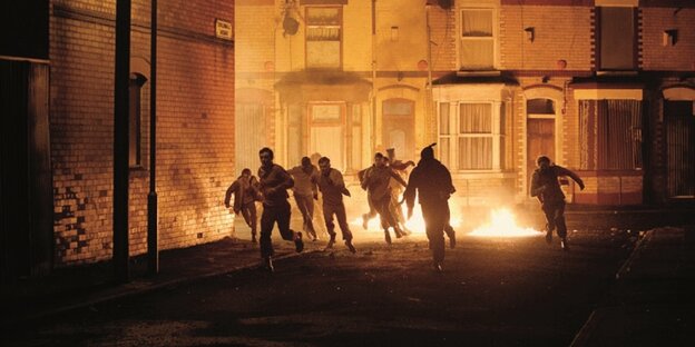 Männer rennen 1971 bei Nacht durch die Straßen der nordirischen Metropole Belfast