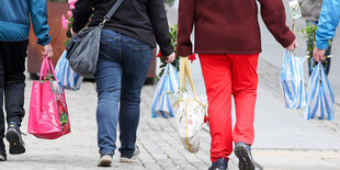 Plastiktüten tragende Passanten von hinten