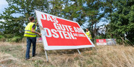 Zwei Männer entfernen ein großes Wahlwerbeplakat. Darauf steht: "Das gute am Osten. Die Linke."
