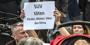 Demonstrierende halten ein Schild hoch:; SUV töten; Kinder, eltern und das Klima