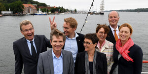 Schleswig-Holsteins Minister scherzen bei einem Fototermin auf einem Boot.