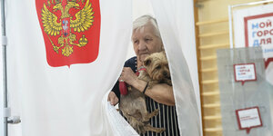 Eine Moskauerin und ihr Hund verlassen nach der Stimmabgabe die Wahlkabine
