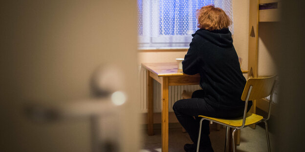 Frau sitzt in einem Zimmer im Frauenhaus Frau sitzt in einem Zimmer im Frauenhaus