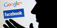 Eine männliche Silhoutte vor einem Bildschirm mit den Schriftzügen von Google und Facebook.