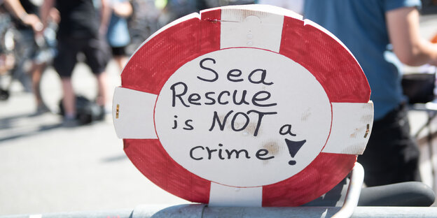 Ein Schild mit der Aufschrift „Sea Rescue is not a crime!“ steht in der Nähe einer Kundgebung der Bewegung „Seebrücke“ in Hamburg.