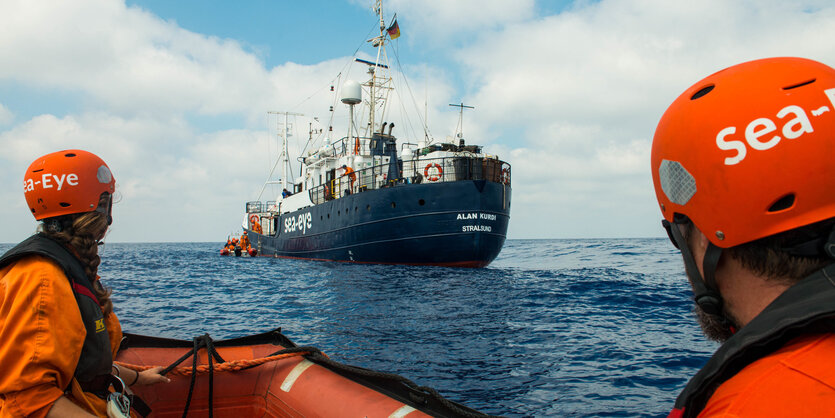 Zwei Seenotretter in einem Schlauchboot, die zum Rettungsschiff „Alan Kurdi“ hinüberschauen