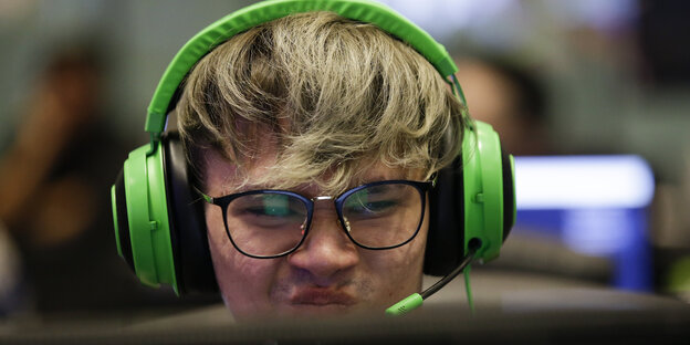 Ein Gamer, der ein grünes Headset trägt, rümpft die Nase