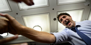 Trudeau von unten fotografiert, schüttelt Hände und lacht begeistert