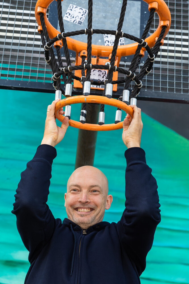 Ein Mann hält sich an einem Basketballkorb fest