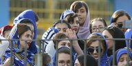 Iranische Frauen stehen hinter einem Gitter und schauen Fußball