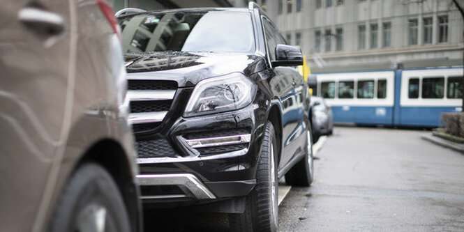 Ein SUV parkt am Straßenrand im Hintergrund fährt eine Tram