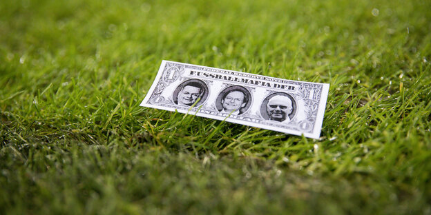 Ein Papierschein der an eine gefälschte Dollarnote erinnert liegt auf dem Rasen