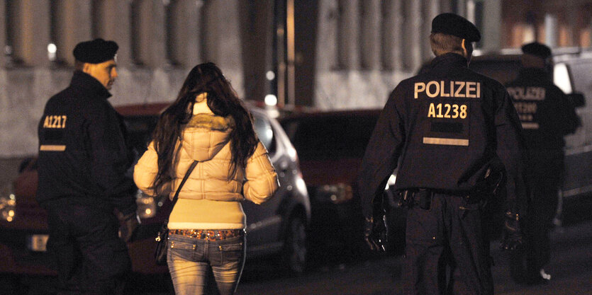 Polizisten begleiten bei einem Polizeieinsatz mit Durchsuchungen am 08.11.2013 in der Kurfürstenstraße in Berlin eine Frau zu einem Kontrollpunkt