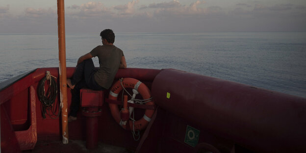 Ein Mann an Deck eines Schiffes, der über das Meer schaut