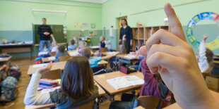 In einer Grundschule melden sich Kinder während des Unterrichts.