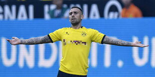 ein Fußballer in einem BVB-Trikot mit ausgebreiteten Armen