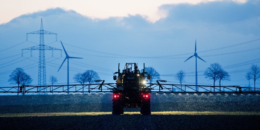 Im Morgengrauen düngt ein Bauer per Traktor sein Feld