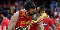 Ein Mann in Basketball-Trikot küsst einen goldenen Siegerpokal