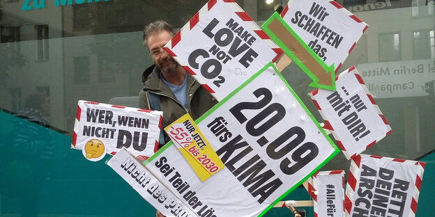 Andreas Prossliner hält ein Schild, auf dem Parolen für den Klimastreik angebracht sind.