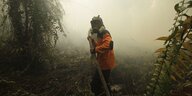 Ein Mann mit Gasmaske und Schlauch, umhüllt von tropischer Vegetation und Rauch
