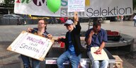 drei junge Männer demonstrieren mit bunten Schildern und Luftballons für Inklusion und gegen die Bluttests