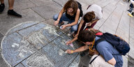 Demonstranten malen die Erde mit Kreide auf den Boden