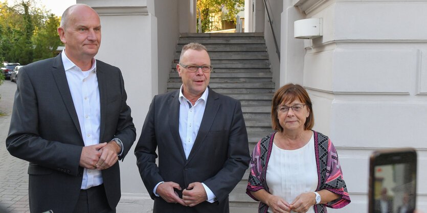 Die drei Vertreter der Parteien stehen nebeneinander, im Hintergrund eine Treppe