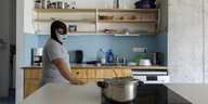 Ein Mann mit Maske steht in einer Küche