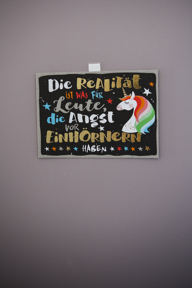 An einer Wand hängt ein Schild mit Einhorn und dem Spruch: