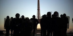 Dunkle Gestalten in Sicherheitkleidung vor dem Pariser Eifelturm