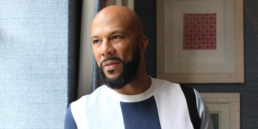 Ein Mann steht an Fenster und schaut hinaus. Es ist der Rapper Common