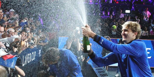 ein Mann duscht das Publikum mit Champagner