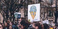 Klimademonstranten halten ein Plakat mit tropfendem Speiseeis hoch
