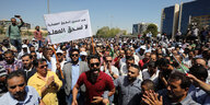 Viele Männer stehen dicht gedrängt, einer hält ein Schild auf dem etwas in arabisch geschrieben steht