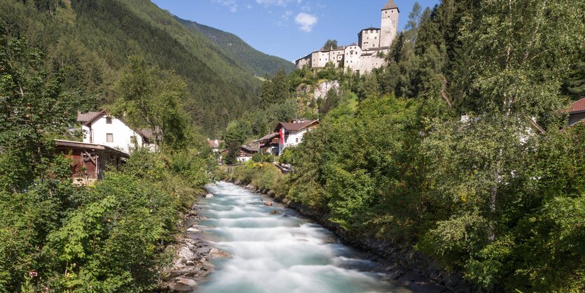 Ein Wildbach zwischen Bergen und grünen Ufern