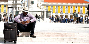 Tourist mit Rollkoffer vor einer palastartigen Fassade