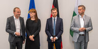 Drei Männer, darunter Michael Kretschmer, und eine Frau stehen vor den Fahnen Europas, Sachsens und Deutschlands