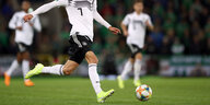 Ein Fußballspieler im Dress der deutschen Nationalmannschaft während eines Spiels, sein Kopf ist nicht im Bild zu sehen