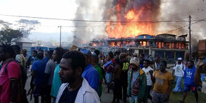 Eine Menschenmenge vor einem brennendem Häuserblock