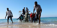 Menschen in und um ein Boot vor der libyschen Küste