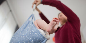 Eine Hebamme wiegt im Rahmen der Nachsorge ein Baby