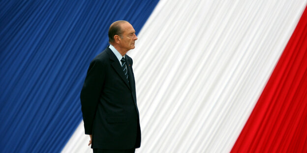 Jaques Chirac steht vor einer übergroßen französischen Flagge
