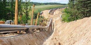 Ein Graben für Leitungen in grüner Landschaft