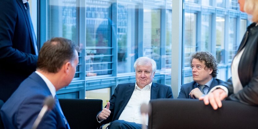 Seehofer sitzt mit Parteikollegen in einer Runde und unterhält sich. Er zeigt mit seiner rechten Hand "Daumen hoch".