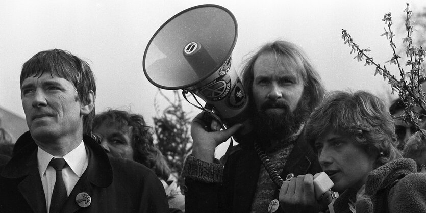 Schwarz-Weiß-Archiv-Aufnahme: Die Gruenen-Politiker Otto Schily, Schatzmeister Lukas beckmann, und Petra Kelly, von links, stehen am 29. Maerz 1983 bei einer Kundgebung mit einem Megafon vor dem Bundestag in Bonn.